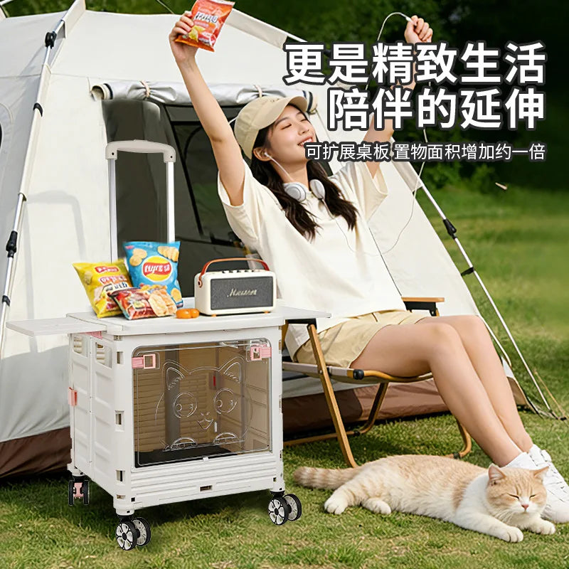 A woman relaxes in a folding chair beside a white rolling storage cart in a grassy outdoor setting with a tent behind her. The cart has a clear front door with a cartoon cat design and small wheels.