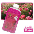 Pink cat litter deodorizing beads with a white lid against a pink rose bush background