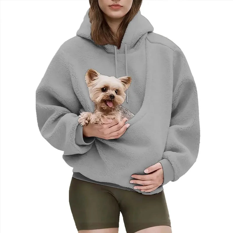 Person wearing a gray hoodie with a dog design, holding a small dog.