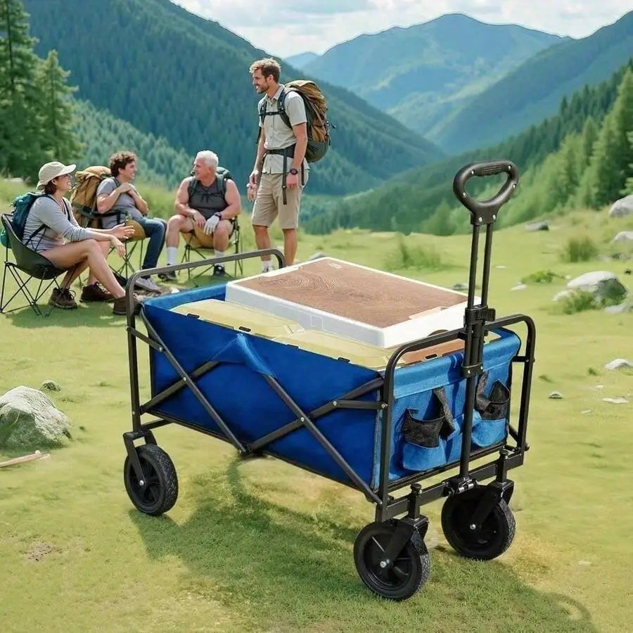 A blue and black folding camping wagon with a handle, shown on a grassy mountain clearing with hikers in the background.