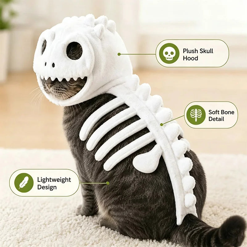 A gray cat wearing a plush dinosaur skeleton costume, sitting on a light beige carpet. The costume includes a white plush skull hood with black eye and nose details, soft white bone-shaped back panels, and text callouts reading 'Plush Skull Hood,' 'Soft Bone Detail,' and 'Lightweight Design.