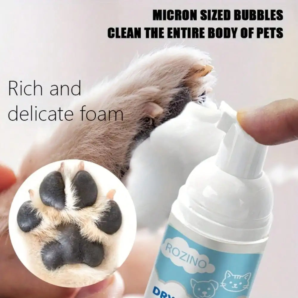 A hand holding a small foam bottle with a white nozzle while applying foam to a cat's paw. Text reads 'MICRON SIZED BUBBLES CLEAN THE ENTIRE BODY OF PETS' and 'Rich and delicate foam.