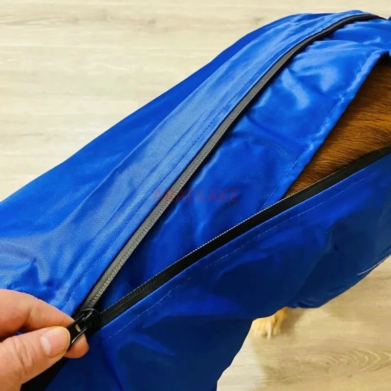 Blue sleeping bag with a hand zipping it up on a wooden floor.