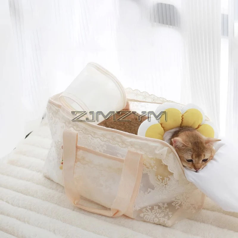 A small orange tabby kitten rests inside a cream-colored lace pet bed with yellow flower-shaped accents, placed on a white textured blanket in front of sheer white curtains.