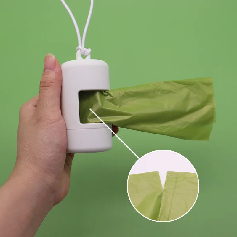 Hand holding a white plastic bag dispenser with a green bag, against a green background.