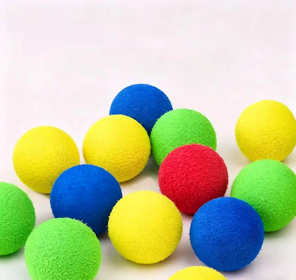 A pile of colorful foam balls in yellow, green, blue, and red on a plain light background.