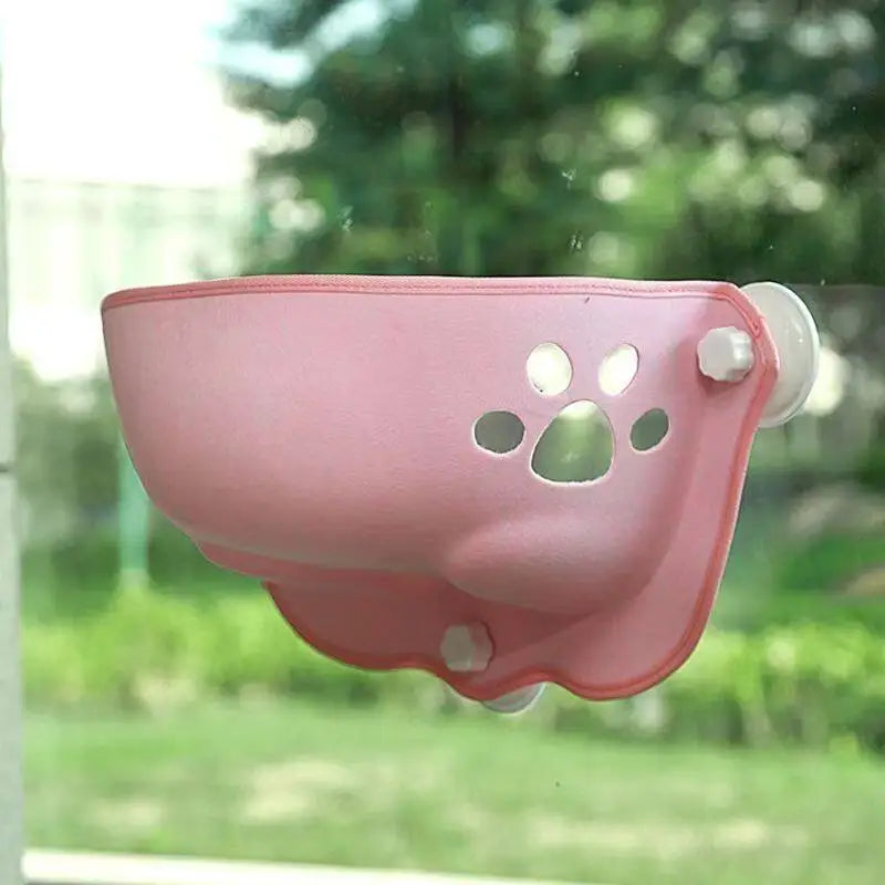Pink pet window feeder with paw design on a glass surface