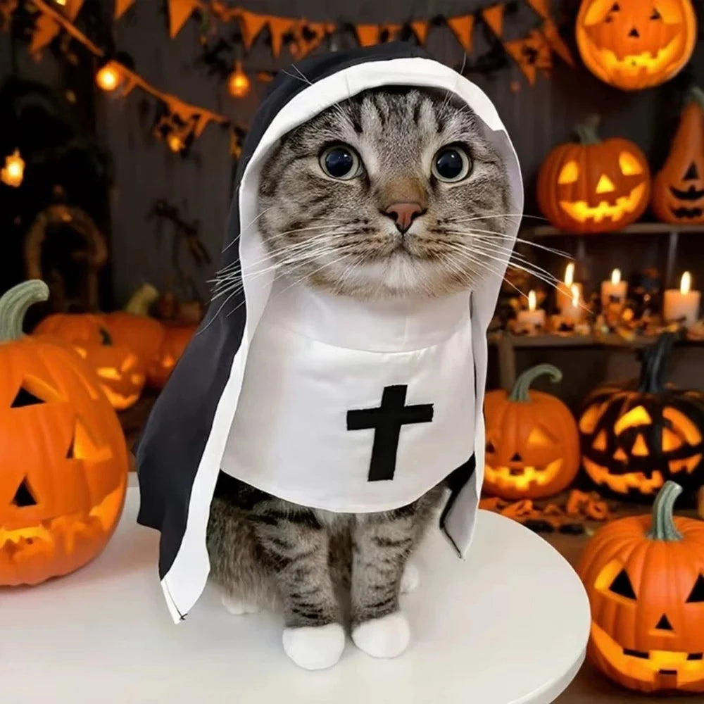 A tabby cat wearing a small nun costume with a white hood and apron featuring a black cross, posed on a white table in a Halloween-themed room with pumpkins and candles.