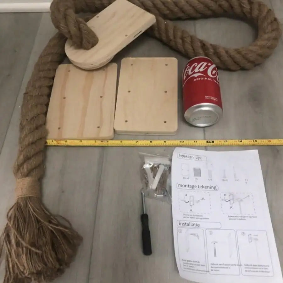 Wooden boards, rope, Coca-Cola can, screwdriver, and installation instructions on a gray surface.