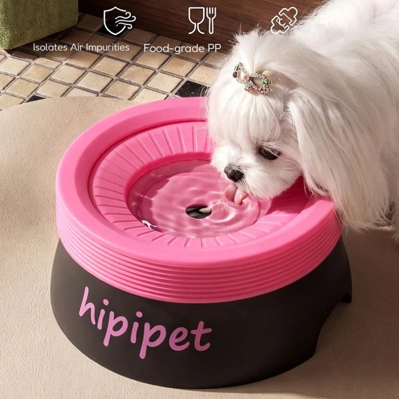 A small white dog with a jeweled hair clip drinks from a pink and black Hipipet elevated pet water fountain. The fountain features a pink top rim and a black base with the brand name 'hipipet' in pink script.