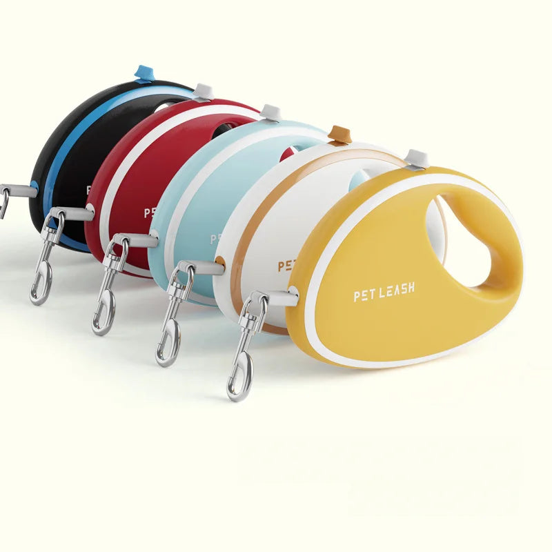 Five retractable pet leashes arranged in a row on a clean off-white background. The leashes are shown in black, blue, red, light blue, white, tan, and mustard yellow, each with a metal clip attached.