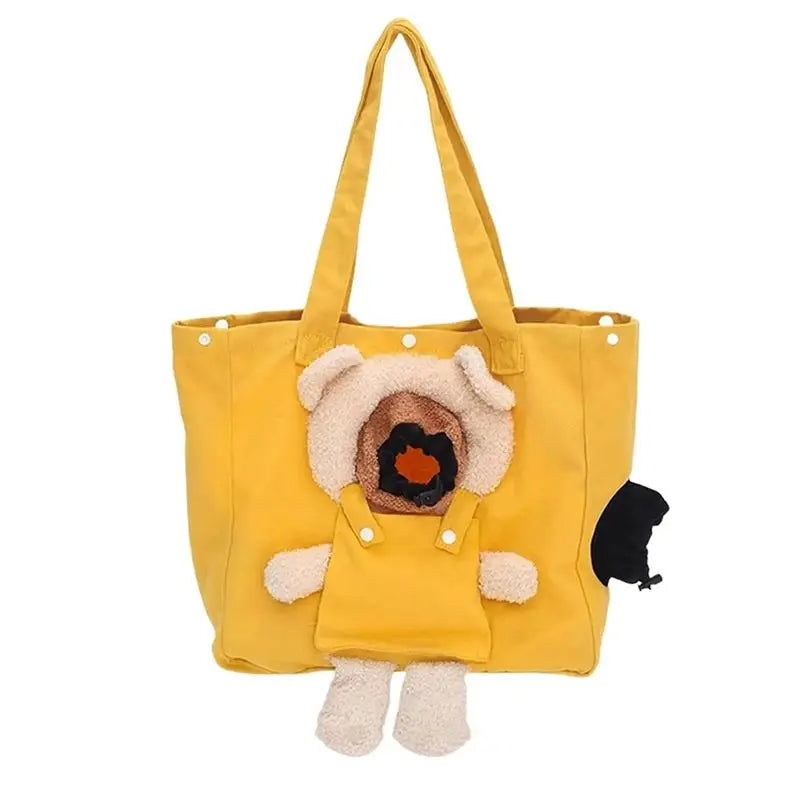 A yellow canvas tote bag featuring a plush dog character attached to the front, with cream-colored ears and paws, a brown face patch, and a small black plush tail on the side.