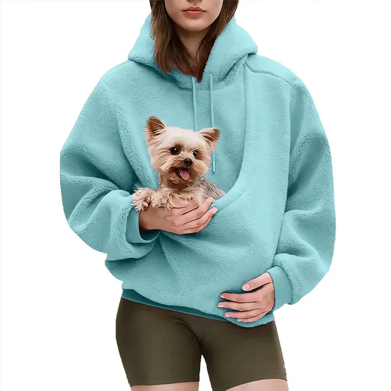 Person wearing a light blue hoodie holding a small dog on a white background