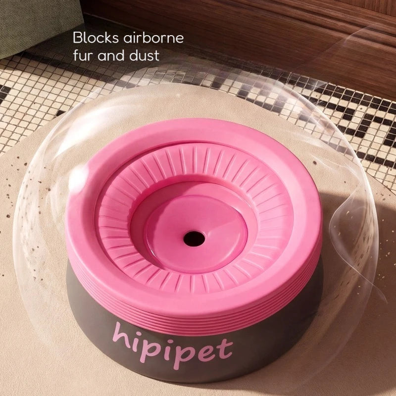 A pink and dark gray hippet pet feeder bowl under a clear protective dome, with the text 'Blocks airborne fur and dust' in the upper left corner.
