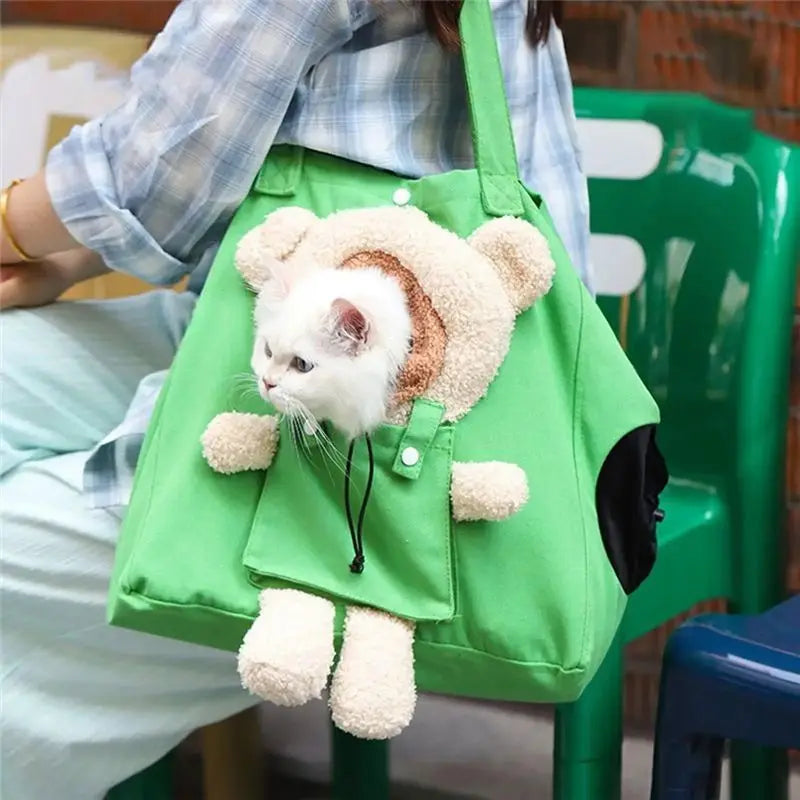A person carrying a bright green pet carrier tote bag with a plush teddy bear face and body protruding from the front, with a white cat peeking out. The person is wearing a blue plaid shirt, and green plastic chairs are visible in the background.