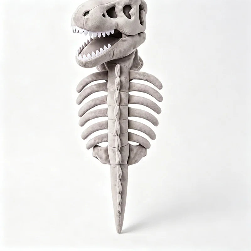 A plush dinosaur skeleton toy with a gray textured body, open mouth showing white teeth, and rib details, photographed against a clean white studio background.