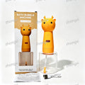 Orange giraffe-shaped bath bubble machine shown next to its retail box, with a clear cylindrical base, small instruction sheet, and USB charging cable on a white background. The product is branded with a heart on its body and has small orange horns.